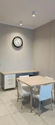 a dining room with a table and chairs and a clock at Menlyn Maine Trilogy Apartment 808 in Pretoria