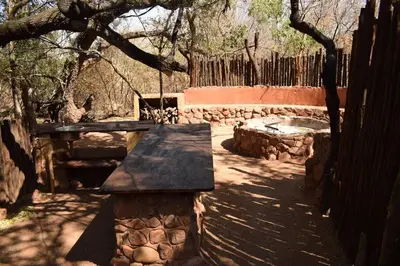 a picnic table and a bench in the shade of a tree at Waterberg Hideaway in Thabazimbi