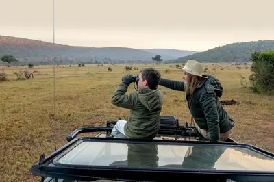 a man and a woman standing on the roof of a vehicle at Ilanga Lodge Welgevonden Game Reserve in Welgevonden Game Reserve