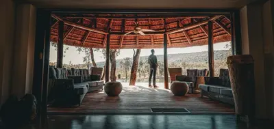 a man standing in the doorway of a room with chairs at Ilanga Lodge Welgevonden Game Reserve in Welgevonden Game Reserve