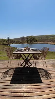 a table and chairs sitting on a deck next to a lake at Ilanga Lodge Welgevonden Game Reserve in Welgevonden Game Reserve