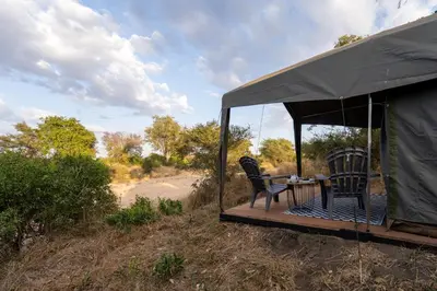 a tent with two chairs and a table on a deck at Kruger Untamed - Tshokwane River Camp in Skukuza