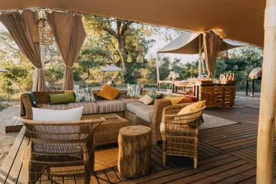 a living room with a couch and chairs on a deck at Kruger Untamed - Tshokwane River Camp in Skukuza
