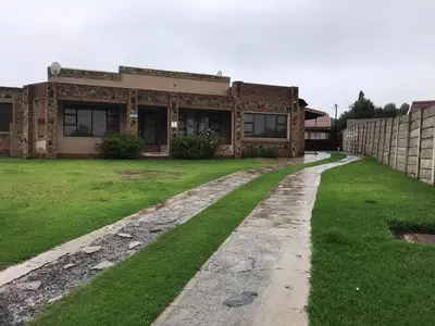 a brick house with a grass yard in front of it at VQS Guesthouse in Ermelo