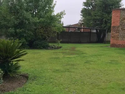 a yard with green grass and a fence at VQS Guesthouse in Ermelo