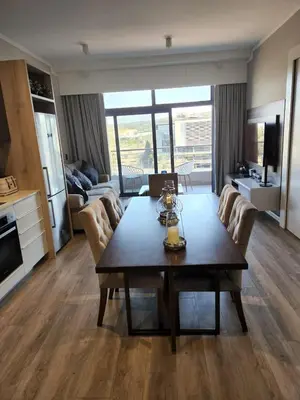 a living room with a dining room table and a kitchen at Menlyn Maine Trilogy Apartment 509 in Pretoria