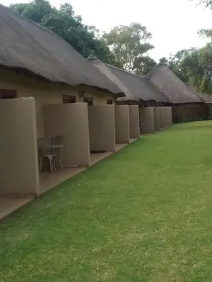 a row of white buildings with a grass yard at Matalatala Wildlife Lodge in Roodeplaat