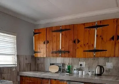 a kitchen with wooden cabinets and a counter top at Matalatala Wildlife Lodge in Roodeplaat