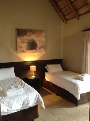 a bedroom with two beds and a painting on the wall at Matalatala Wildlife Lodge in Roodeplaat