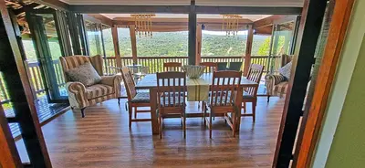 a dining room with a table and chairs on a porch at Loskop Serene Bush Cabin in Winterkamp