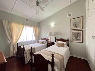a bedroom with two beds and a ceiling fan at Palm House Accomodation in White River