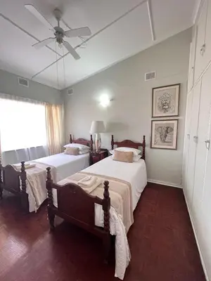 a bedroom with two beds and a ceiling fan at Palm House Accomodation in White River