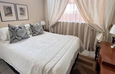 a bedroom with a white bed with pillows and a window at Palm House Accomodation in White River
