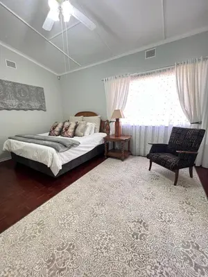 a bedroom with a bed and a chair and a window at Palm House Accomodation in White River