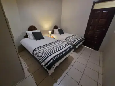 two twin beds in a room with a door at Hoep Hoep Self Catering in Groblersdal