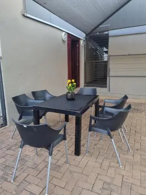 a black table and chairs with a vase of flowers on it at Hoep Hoep Self Catering in Groblersdal