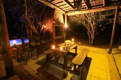 a table and a bench on a patio at night at SouthernCross@Kruger in Marloth Park