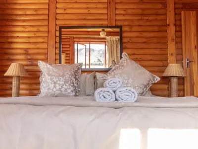 a bed with white pillows and towels on it at Moopong Farm House in Dullstroom