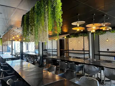 a dining room with tables and chairs and plants at Riverleaf Hotel in Brits