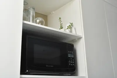 a microwave in a white cabinet with a shelf at Falcons Rest in Pretoria