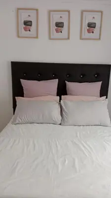 a bed with white sheets and pink pillows at NEMARA Self Catering Lodge in Polokwane