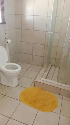 a bathroom with a toilet and a shower with a rug at NEMARA Self Catering Lodge in Polokwane
