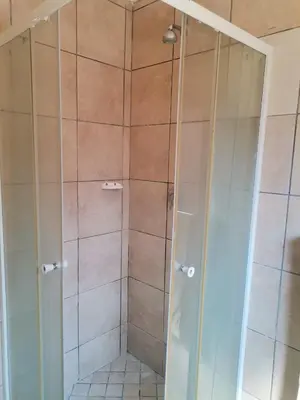 a shower with a glass door in a bathroom at NEMARA Self Catering Lodge in Polokwane