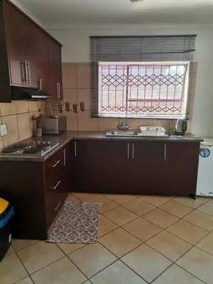 a kitchen with brown cabinets and a window in it at NEMARA Self Catering Lodge in Polokwane
