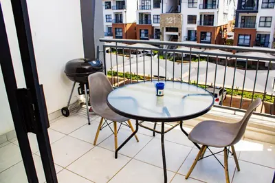a table and chairs on a balcony with a view of a street at 1368 The Blyde Crystal Clear 1 Bedroom Apartment in Pretoria