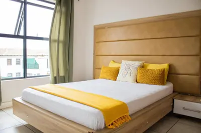 a bedroom with a large bed with yellow pillows at 5 The Blyde Crystal Clear 2 Bedroom Apartment in Pretoria