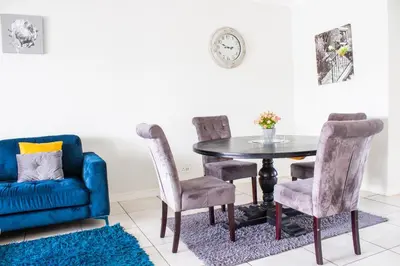 a dining room with a blue couch and a table and chairs at 507 The Blyde Crystal Clear Lagoon 2 Bedroom Apartment in Pretoria