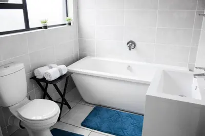 a bathroom with a tub and a toilet and a sink at 507 The Blyde Crystal Clear Lagoon 2 Bedroom Apartment in Pretoria
