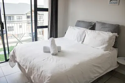 a white bed with a stuffed animal on top of it at 507 The Blyde Crystal Clear Lagoon 2 Bedroom Apartment in Pretoria