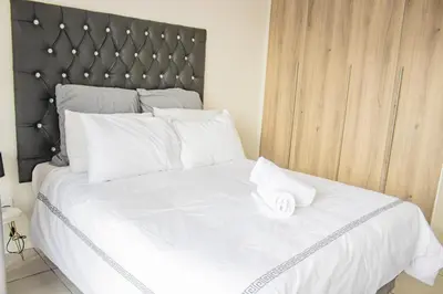 a white bed with a black headboard and white pillows at 507 The Blyde Crystal Clear Lagoon 2 Bedroom Apartment in Pretoria