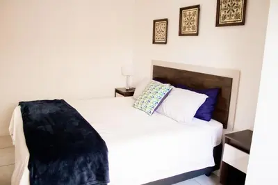 a bedroom with a bed with white sheets and blue pillows at 1523 The Blyde Crystal Clear 2 Bedroom Apartment in Pretoria