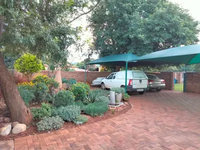 a garden with a blue umbrella and a car at At Home Apartments in Mokopane