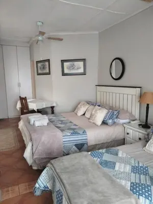 a bedroom with two beds and a table and a desk at At Home Apartments in Mokopane