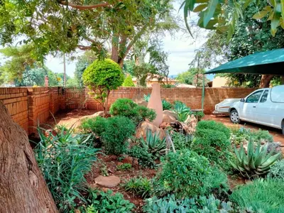 a garden with plants and a fence and a car at At Home Apartments in Mokopane