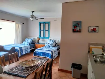 a living room with two beds and a table at At Home Apartments in Mokopane