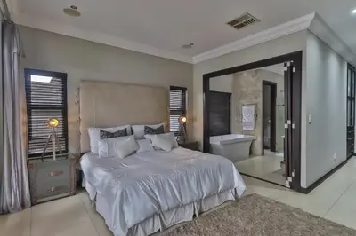 a bedroom with a large bed and a bathroom at The Pecan Lake Guesthouse in Hartbeespoort