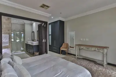 a bedroom with a bed and a desk and a sink at The Pecan Lake Guesthouse in Hartbeespoort