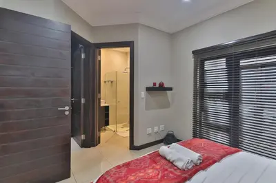 a bedroom with a bed and a large window at The Pecan Lake Guesthouse in Hartbeespoort
