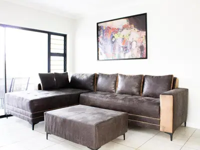 a living room with a brown leather couch and a ottoman at 1253 The Blyde Crystal Clear 3 Bedroom Garden Apartment in Pretoria