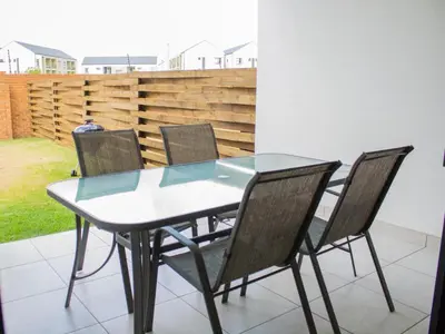 a glass dining table with four chairs around it at 1253 The Blyde Crystal Clear 3 Bedroom Garden Apartment in Pretoria