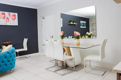 a dining room with a table and chairs and a mirror at 1517 The Blyde Crystal Clear 3 Bedroom Garden Beachfront in Pretoria