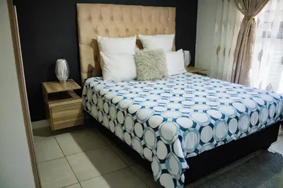 a bedroom with a bed with a blue and white comforter at 1517 The Blyde Crystal Clear 3 Bedroom Garden Beachfront in Pretoria