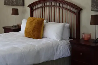 a white bed with a wooden headboard and white pillows at The Meander Estate in Balmoral