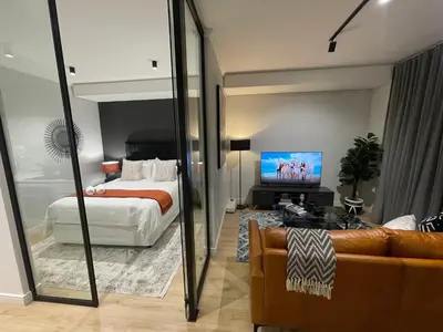 a bedroom with a bed and a tv and a couch at Exec Oasis @Ellipse in Midrand