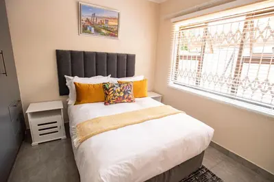a bedroom with a large bed with a large window at Colourfully cosy in Pretoria