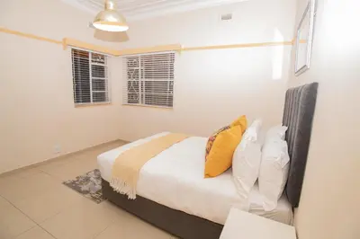 a bedroom with a bed with yellow pillows at Colourfully cosy in Pretoria
